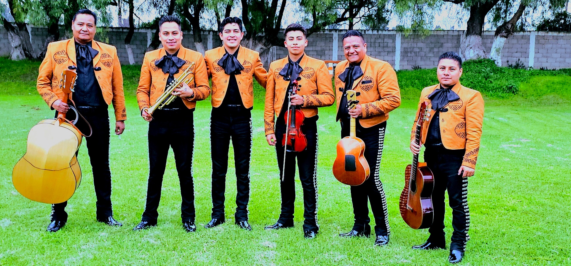 Mariachi posando con instrumentos en el campo